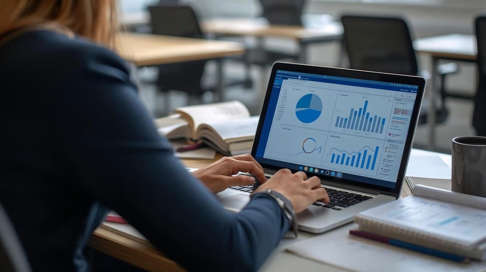 Woman working on laptop with charts and graphs.