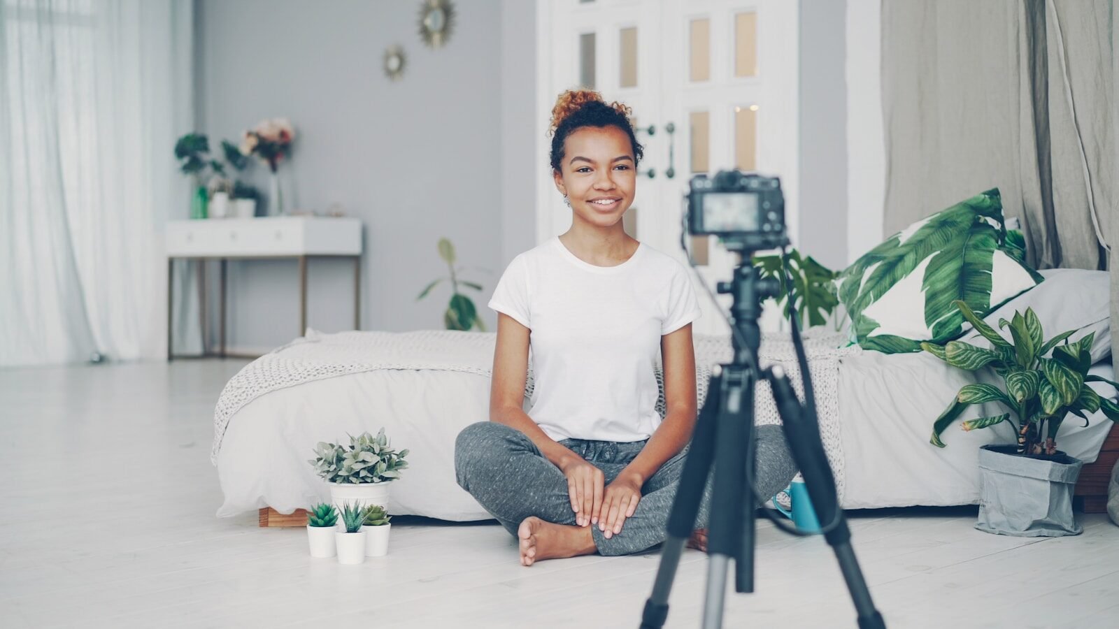 Young woman sitting on floor filming with camera.